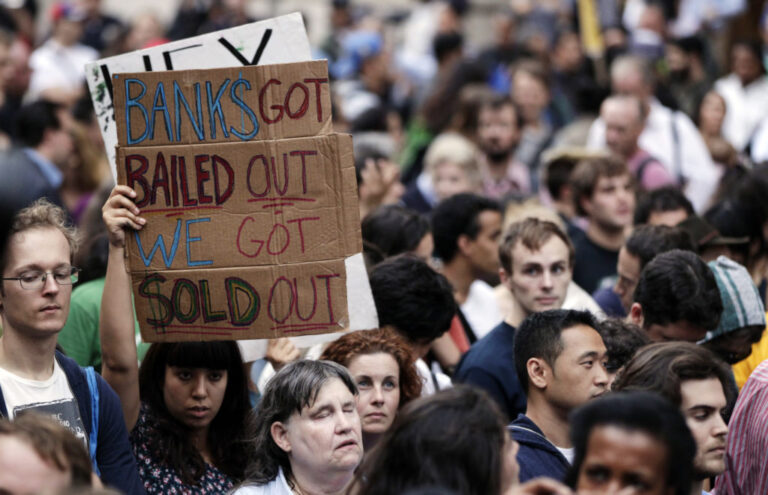 A demonstrator from the Occupy Wall Street campaign holds aloft a sign as the march enters a courtyard near the New York Police Department headquarters in New York