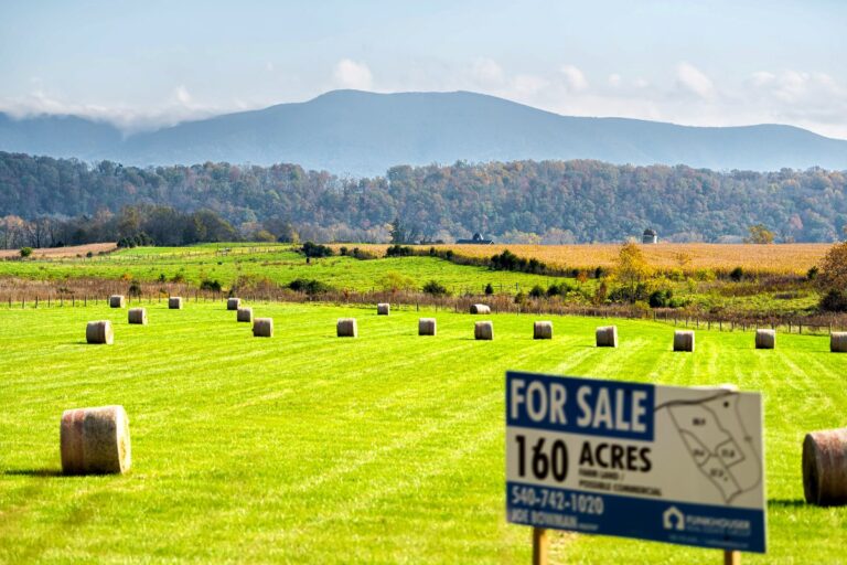 Hay roll bales on countryside field in Shenandoah Valley Virginia mountains with sign for acres for sale